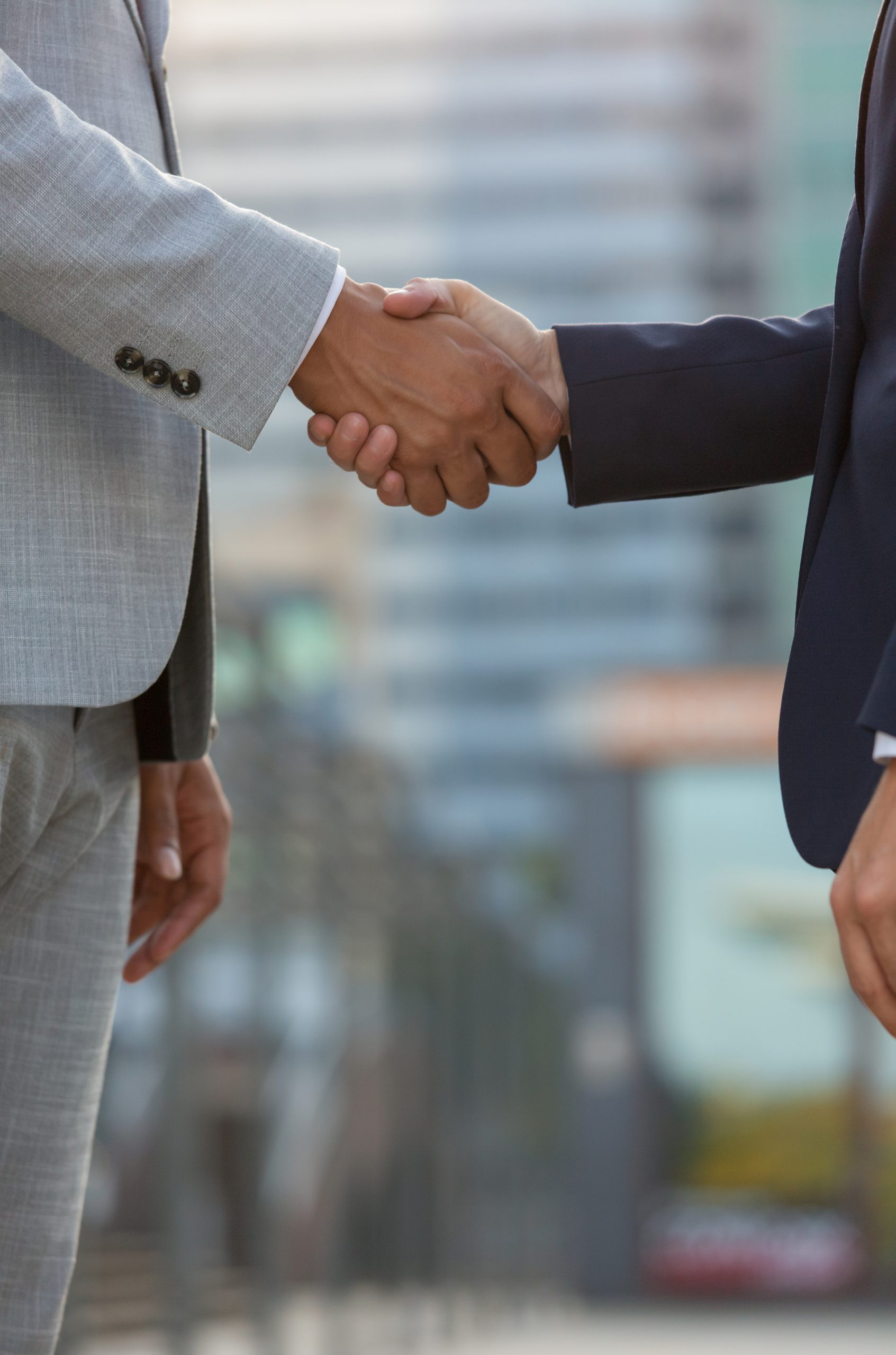 businesspeople standing in city street and shaking hands